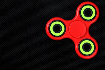 Close-up shot of red-green fidget finger spinner on black background. Top view