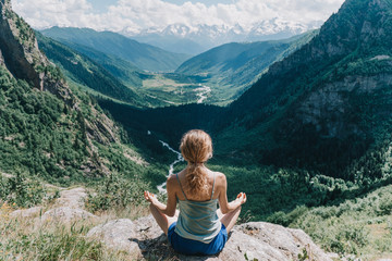young girl meditates on a background of mountains