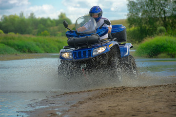 Man on ATV rides on the river in the summer.