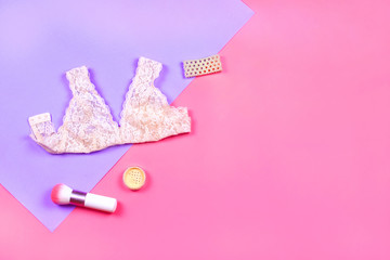 Flat lay of woman lingerie, bracelet and cosmetics. Pink and violet background. 