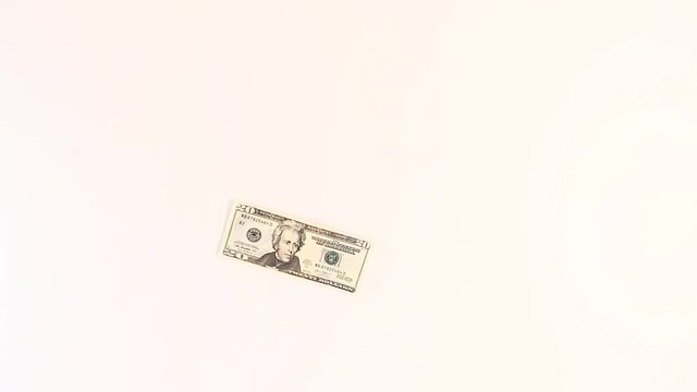 Twenty-dollar bill of the United States slowly falls on a white background.
