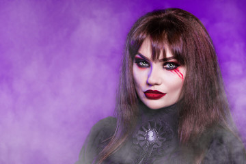 Witch, a vampire in a black gothic dress on a purple background. Portrait. American, dress for a costume party Halloween. Bright makeup