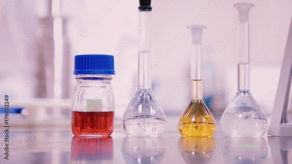 Aufkleber laboratory flasks and beakers with liquids of different colors on lab table