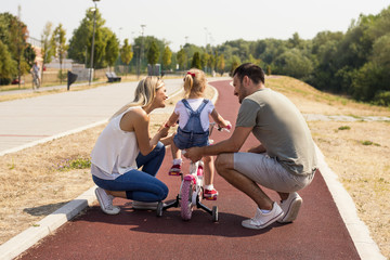 Parents teaching daughter to ride a bicycle for the first time
