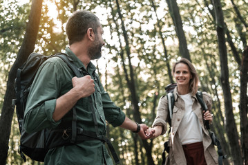 Happy man leading hand of woman in forest