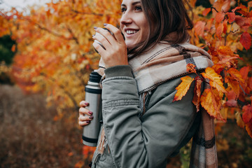 Young woman drinks tea in autumn forest