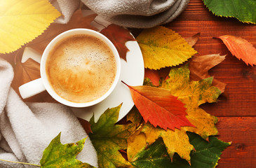 autumn background with a cup of hot aromatic coffee on a wooden table surrounded by autumn leaves...