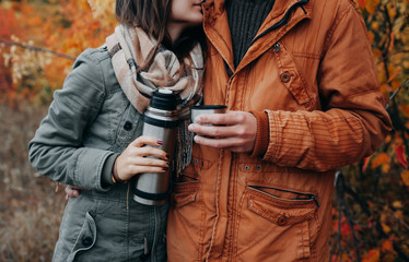 Young couple drinks hot tea in autumn forest