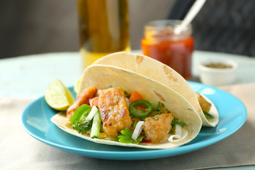 Plate with delicious fish tacos on table