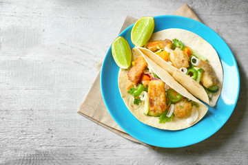 Plate with delicious fish tacos on table