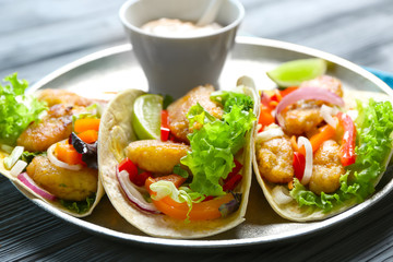 Plate with delicious fish tacos on table, closeup