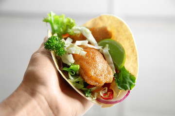 Hand of woman holding delicious fish taco, closeup