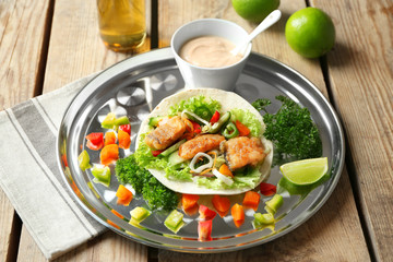 Tray with delicious fish taco on wooden table