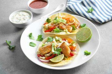 Plate with delicious fish tacos on table