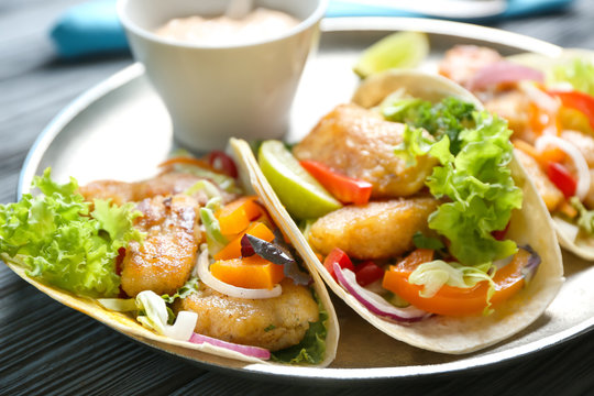 Plate with delicious fish tacos on table, closeup