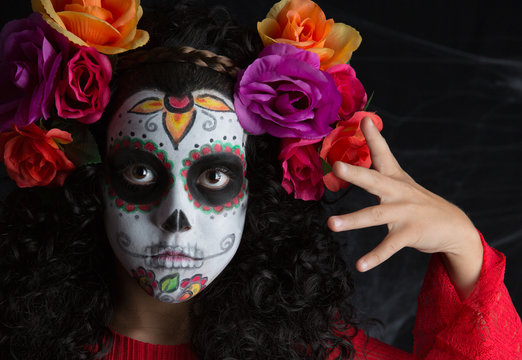 Little girl with Halloween costume and makeup of La Calavera Catrina with white painted face
