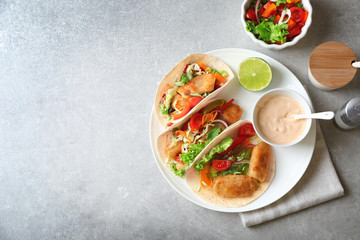 Plate with delicious fish tacos on table
