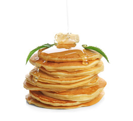 Pouring honey onto stack of tasty pancakes on white background