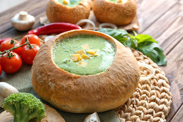 Broccoli soup with cheese in bread loaf on table