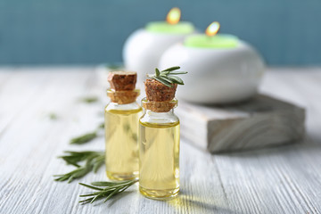 Bottles with rosemary oil and herb on wooden table