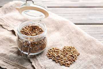 Glass jar and heart made of hemp seeds on sackcloth