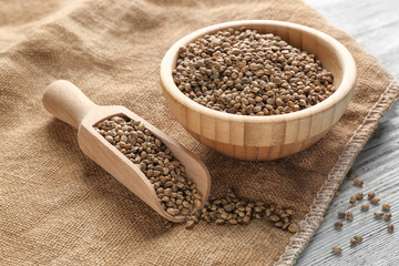 Wooden bowl and scoop with hemp seeds on table