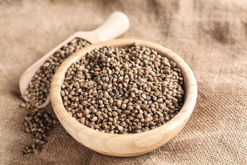 Wooden bowl and scoop with hemp seeds on table