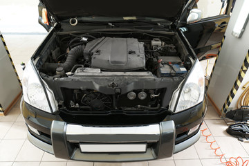 Car with open hood in body shop