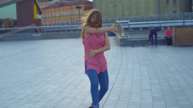 young attractive woman on a bridge on the river bank. modern extreme dances in the style of hip-hop and classical ballet. the girl rhythmically moves to the music. The girl uses a handrail as a dance