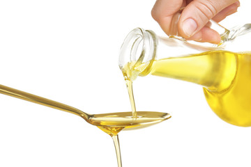 Pouring cooking oil into spoon on white background