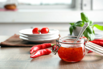 Composition with tasty chili sauce in jar on table