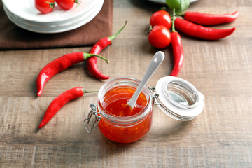 Composition with tasty chili sauce in jar on table