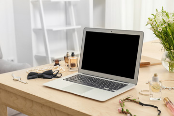 Comfortable workplace with modern laptop and female accessories on table
