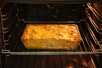 Baking tray with spinach lasagna in oven