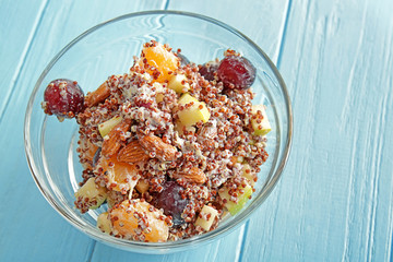 Glass bowl with quinoa salad on color wooden background