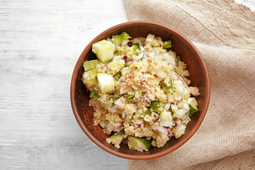 Bowl with quinoa salad on wooden table