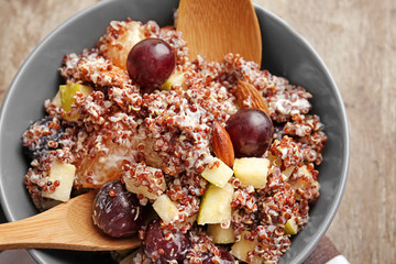 Mixing quinoa salad on wooden background