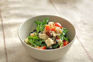 Bowl with quinoa salad on table