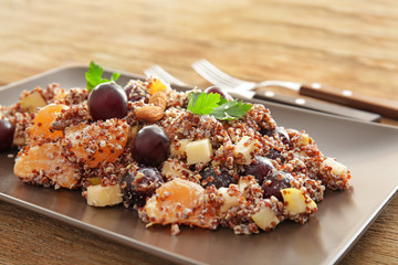 Plate with quinoa salad on wooden table, closeup