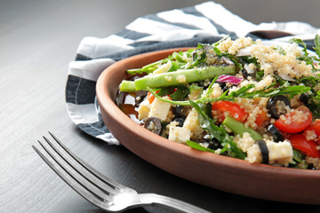 Wooden plate with quinoa salad on table, closeup