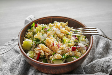 Bowl with quinoa salad on table