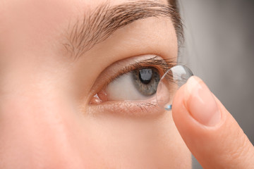 Fototapeta premium Young woman putting contact lens, closeup