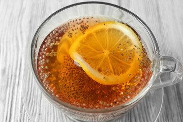 Cup of tea with chia seeds and lemon slice on table, closeup