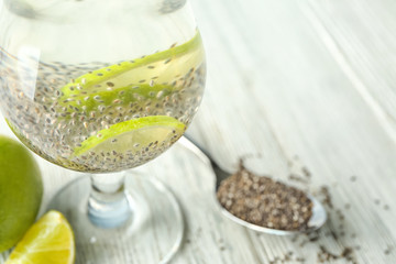 Glass of water with chia seeds and lime slices on table, closeup