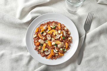 Plate with tasty brown rice, mushrooms and vegetables on table