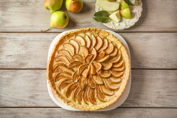 Plate with tasty pear tart on wooden table