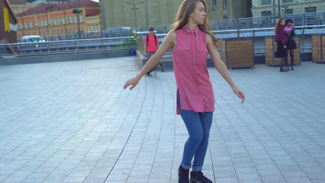 young attractive woman on a bridge on the river bank. modern extreme dances in the style of hip-hop and classical ballet. the girl rhythmically moves to the music. The girl uses a handrail as a dance