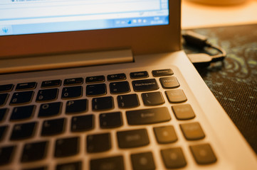 Close-up of laptop keyboard with focus on Backspace button and highlighted with warm evening light