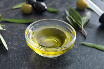 Glass bowl with olive oil on dark background