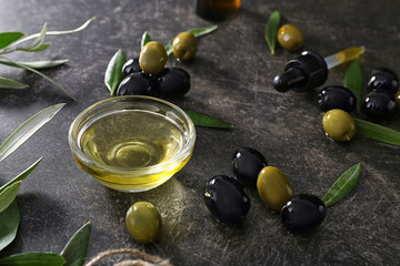 Glass bowl with olive oil on dark background